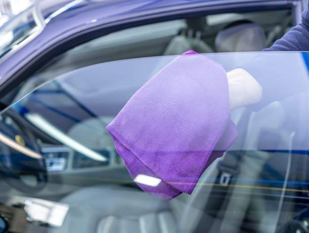 manual leaning of luxury car windows with a microfiber towel